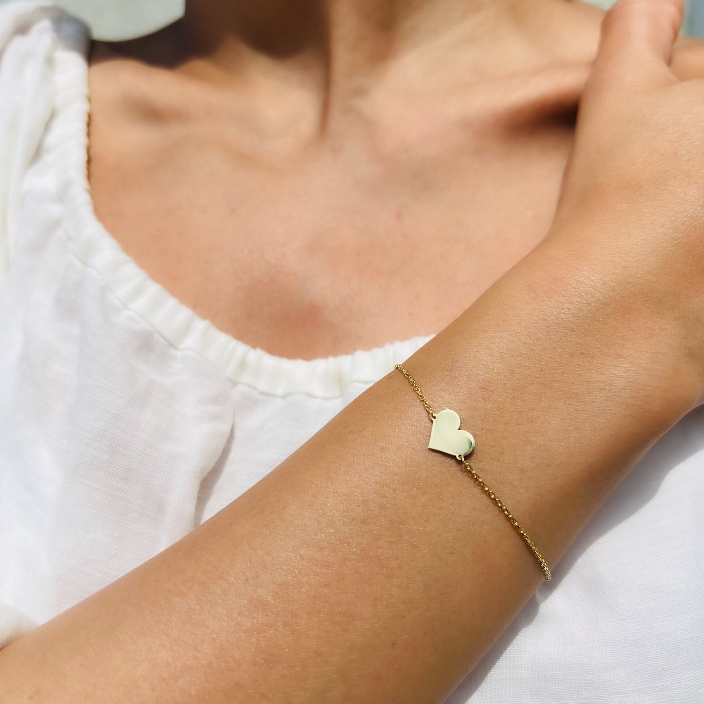 Enti Jamila bracelet, handmade in 18k gold with heart charm design, worn on a wrist in natural light.