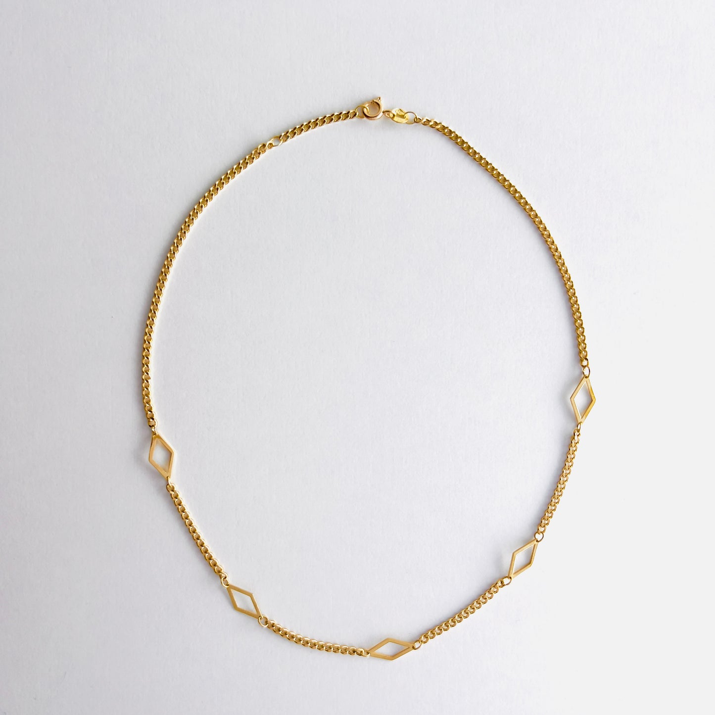 Enti Leila necklace, handmade in 18k gold with a sleek diamond-shaped geometric pendant and gold chain, displayed on white background