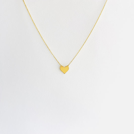Enti Jamila necklace, handmade in 18k gold with a delicate heart charm and gold chain, displayed on white background
