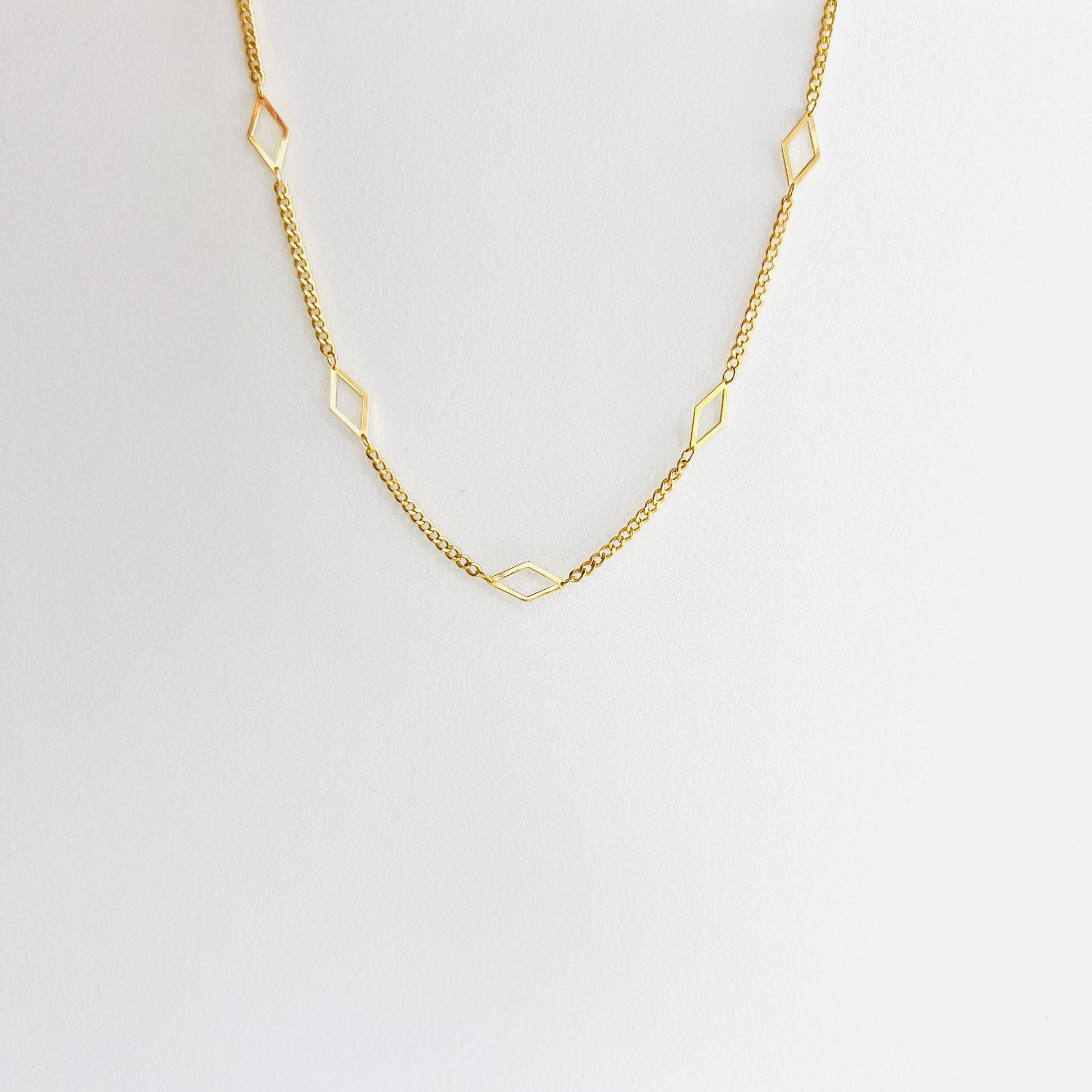 Enti Leila necklace, handmade in 18k gold with a sleek diamond-shaped geometric pendant and gold chain, displayed on white background