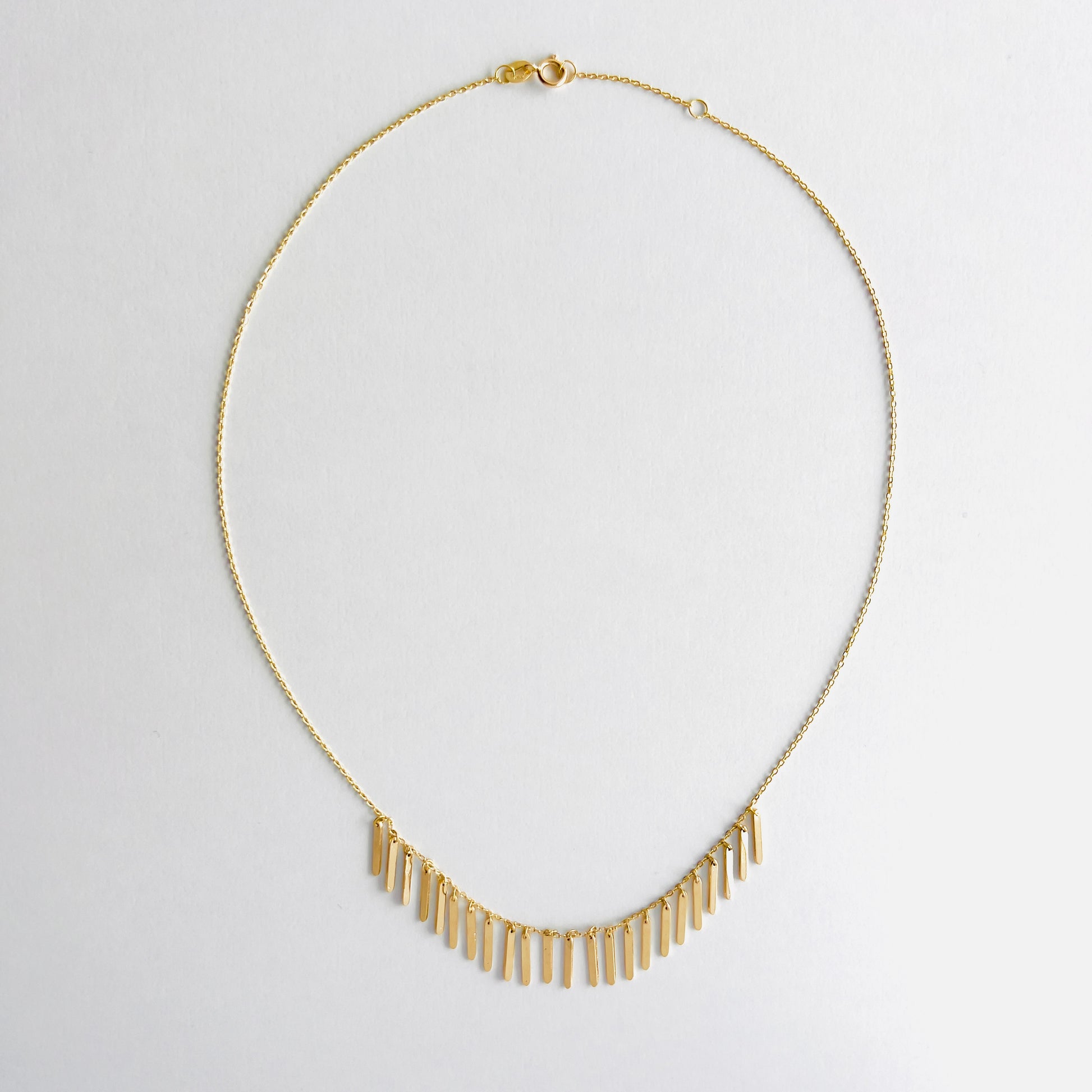 Enti Samira necklace, handmade in 18k gold with small light-catching pendants and gold chain, displayed on white background